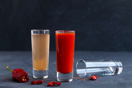 tomato cocktail.two tequila shots on black background. Sangrita is a Mexican traditional alcohol...