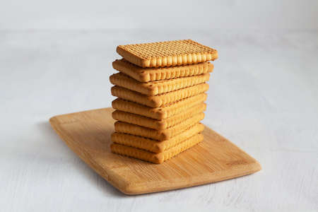 stacks of tasty cookies on the cutting board. square biscuits on the white table with copy space....