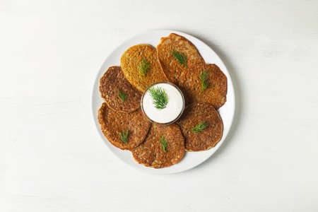 toasted Potato pancakes with sour cream, herbs on the white background. Belarusian cuisine. potato pancakes on the plate with copy space. flat lay. Traditional Jewish latkes for Hanukkah. top viewの写真素材