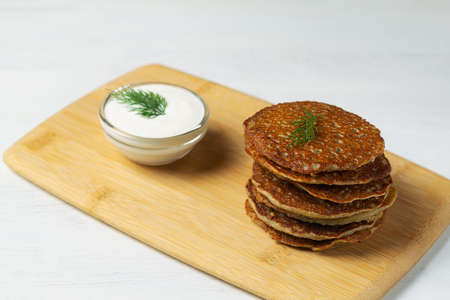 stacks of toasted Potato pancakes with white sour cream, green herbs on the cutting board. Belarusian cuisine. potato pancakes on the white background with copy space.の写真素材