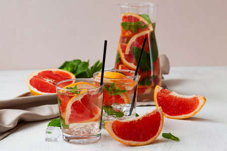 fruit cocktail.Cocktail grapefruit with fruits. fresh Grapefruit juice with green mint on beige background. Glass and jug of grapefruit lemonade. Refreshing summer drinks.の写真素材