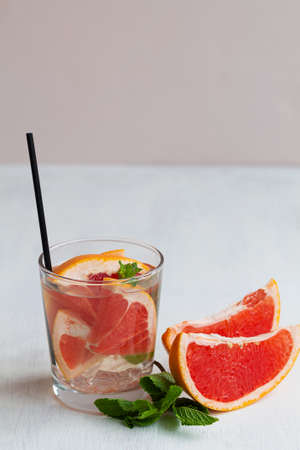 cocktail with fruits.Refreshing summer drinks on the white table. glass of Cocktail grapefruit. fresh Grapefruit lemonade with green mint on beige background. copyspace. verticalの写真素材