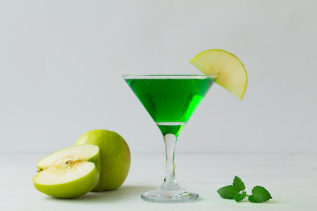 Apple cocktail mixed drink with vodka and apple slice. Apple martini cocktail on the white background. Homemade Green Alcoholic drinks in martini glasses with apple slice.の写真素材