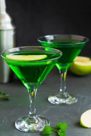 martini with mint.Apple cocktail mixed drink with vodka and apple slice. Apple martini cocktail on the black background. Green Alcoholic drinks in martini glasses with apple slice.の写真素材