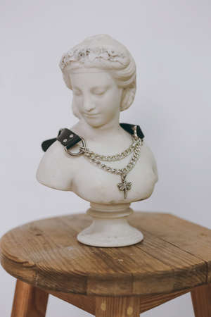 A chic necklace made of leather and chain hangs on a plaster figureの写真素材