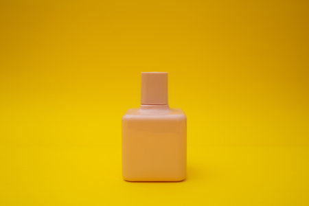 Pink bottle of perfume on a yellow backgroundの写真素材