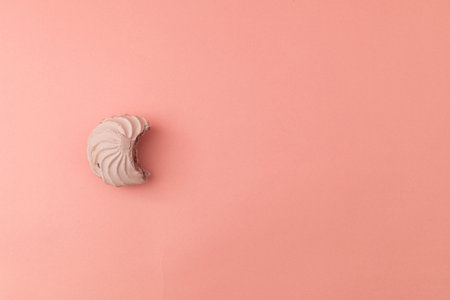Pink bitten marshmallow on pink background, candy monochromeの写真素材