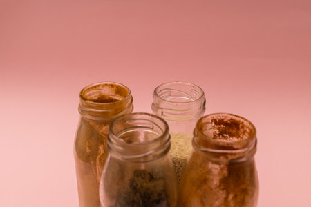 Spices in glass jars on a pink backgroundの写真素材