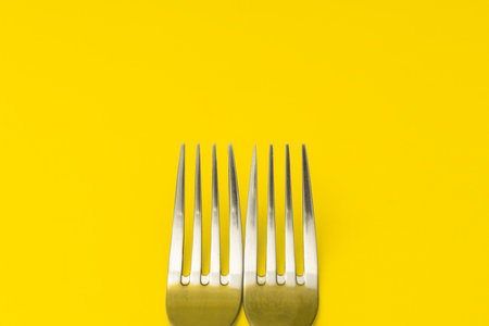 Silver forks lie on a yellow background, minimalismの写真素材