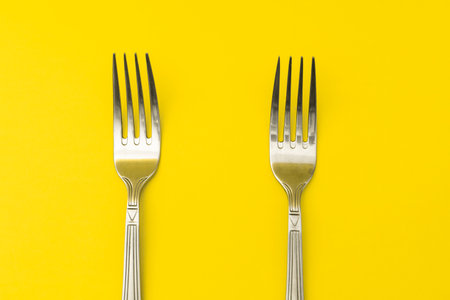 Silver forks lie on a yellow background, minimalismの写真素材