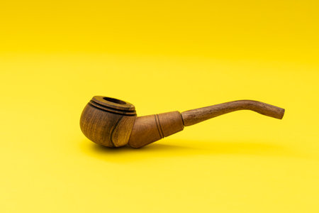 Wooden smoking pipe with tobacco on a yellow background, smoking harmsの写真素材