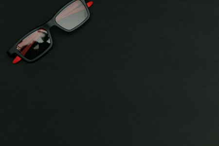 Black sunglasses lying on a black background