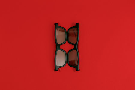 Black sunglasses lying on a red backgroundの写真素材