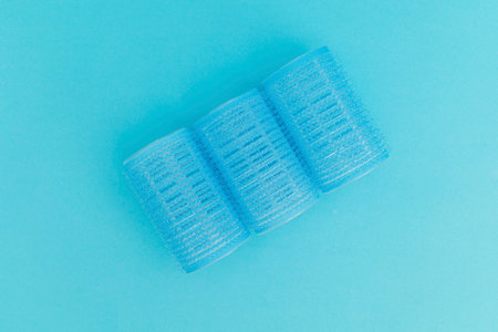 Large hair curlers on blue background, monochrome