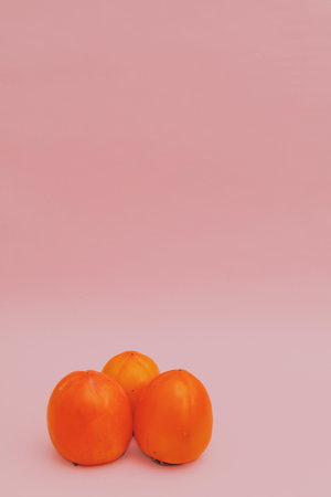 Juicy orange persimmon on a pink background