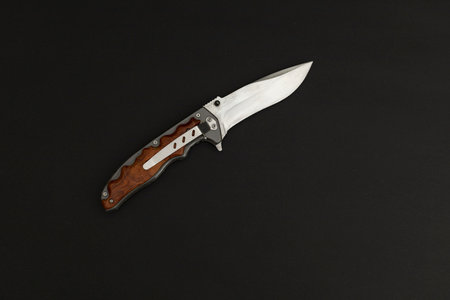 hunting knife with wooden handle isolated on black background, top view