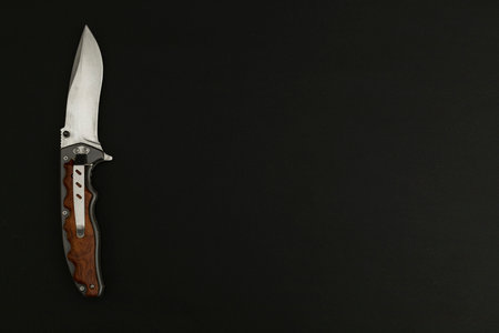 Hunting knife on black background, top view. Space for text