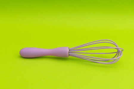 Purple whisk for the kitchen on a green background