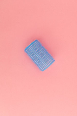 Blue hair curlers on a pink background
