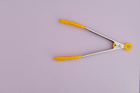 Yellow pasta tongs on purple backgroundの写真素材