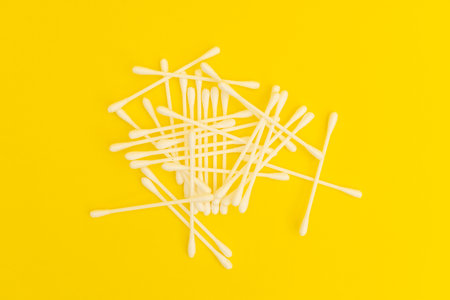 White cotton swabs on a bright yellow background