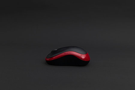 Black computer mouse with red stripe on black background