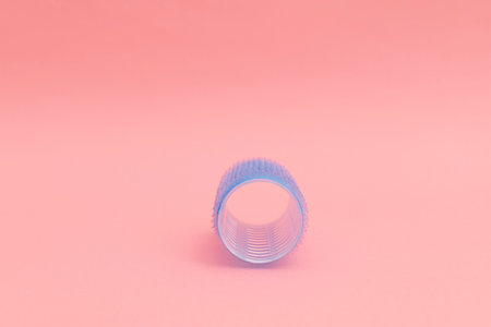 Large blue hair curlers on a bright pink background