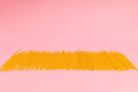 Raw macaroni scattered on pink backgroundの写真素材