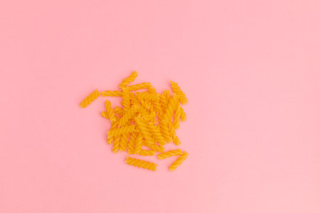 Raw macaroni scattered on pink backgroundの写真素材