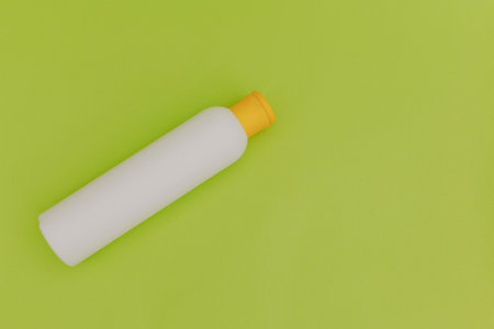 Shampoo for hair in a white package with a yellow cap on a green backgroundの写真素材