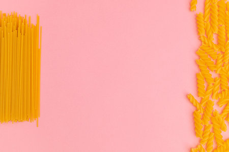 Raw macaroni scattered on pink backgroundの写真素材
