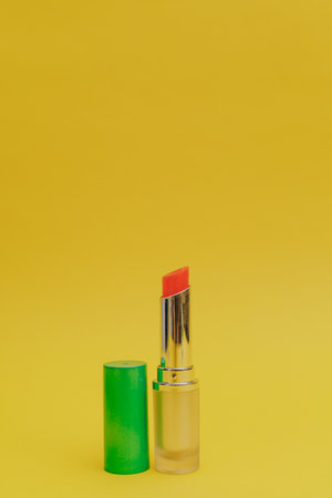 Lipstick with a bright green cap on a yellow backgroundの写真素材