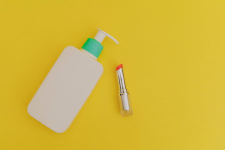 White bottle of makeup and lipstick on a yellow backgroundの写真素材