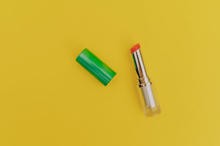 Lipstick with a bright green cap on a yellow backgroundの写真素材