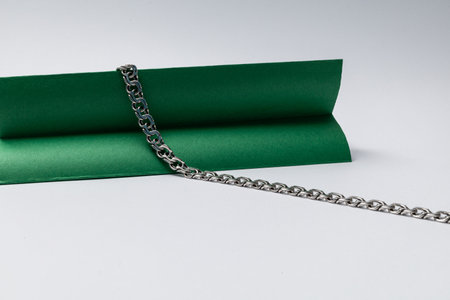 Silver chain with unusual shape on white background with green decorations