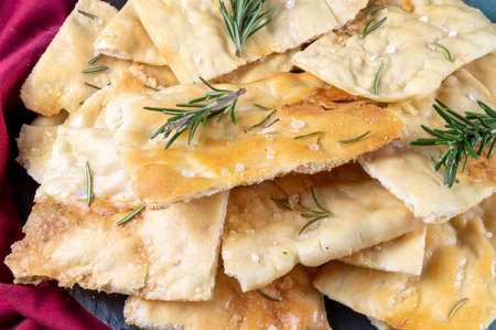 White Roman pizza with rosemary and coarse salt in closeup. Roman focaccia. Scrocchiarella.