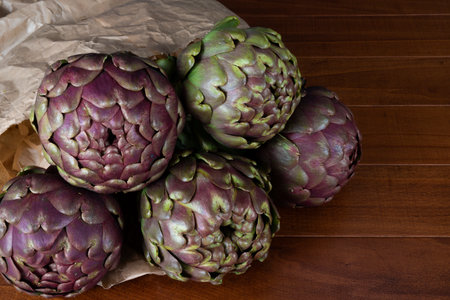 Roman artichokes on the wooden table. Fresh and raw artichokes.の写真素材