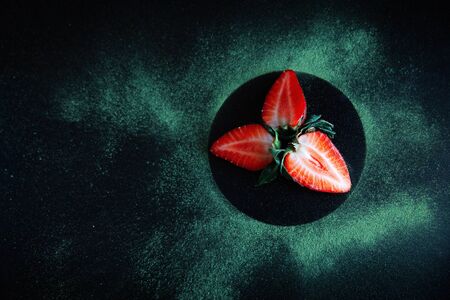 Top view of red strawberries in a black circle on the table with spilled matcha aroundの写真素材