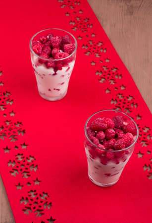 Two glasses of raspberry dessert on a red table-clothの写真素材