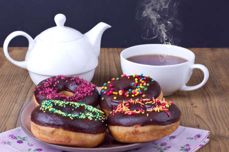 Traditonal american donuts with a cup of tea serving on a tableの写真素材