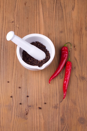 Pepper in mortar with pestle with chili pepper on wooden backgroundの写真素材