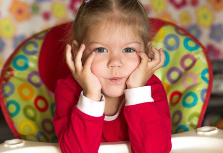 portrait of thinking and sad little girl propping head by hands looking at cameraの写真素材