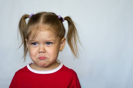Portrait of sad little girl with blue eyes looking aside on the white backgroundの写真素材