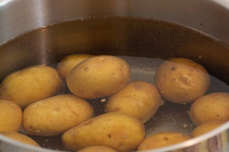 Potato with skin on cooking in water in potの写真素材