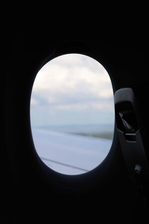 View on sky and clouds from the porthole on airplaneの写真素材