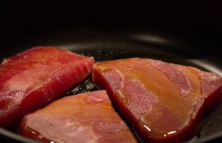 Three slices of raw tuna fillet on pan with oilの写真素材