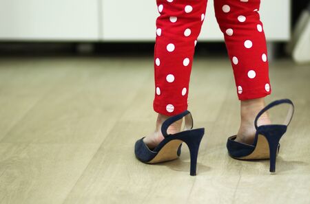 Heels with large size on legs of little girlの写真素材
