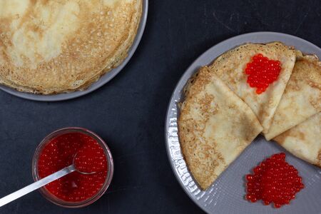 Blini triangles or crepes with red caviar on the plate with jarの写真素材