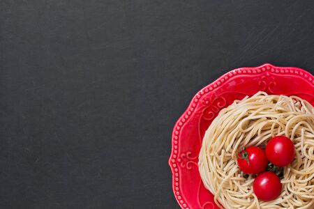 Top view durum wheat spaghetti on red plate on the black backgroundの写真素材
