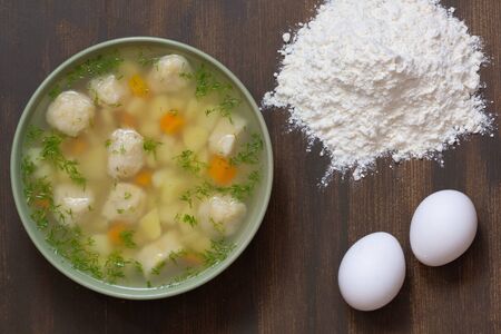 Top view of soup in bowl with dumplings on the wooden backgroundの写真素材